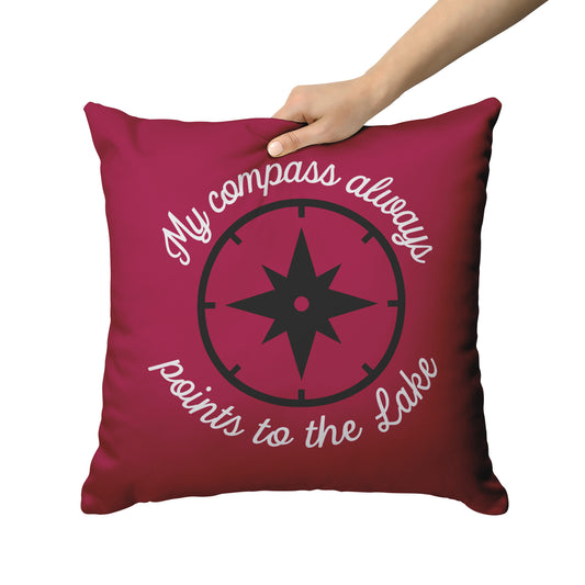 Cranberry pillow with script "My compass always points to the lake" in white around a black compass.